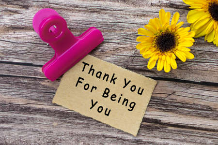 Thank you for being you text on torn brown paper with paper clip holder on wooden surface. Motivational quote.の写真素材