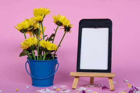 Note paper with frame and and dahlia yellow flowers in blue bucket on pink background. Copy space.の写真素材