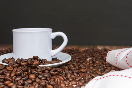 Cup of coffee on coffee beans and blurred background.
