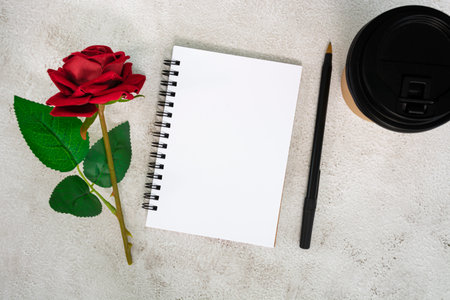 Note book with disposable coffee cup, pen and roses on white marble table.. Directly above. Flat lay. Copy space.の写真素材