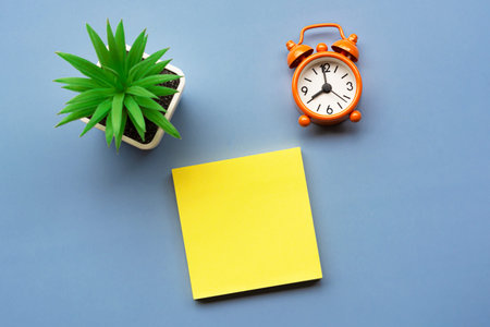 Adhesive Note with potted plant and alarm clock set at 8 o'clock against blue background. Business...
