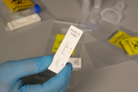 Doctor holding a NEGATIVE test kit for disease COVID-19 with blurred background of lab card kit for...