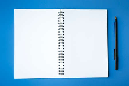 Top view of pen and notepad on blue background. Copy space. Flat lay.の写真素材