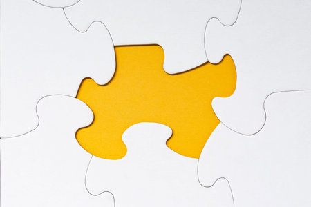 White jigsaw puzzle with some missing pieces on yellow background. Copy space.の写真素材