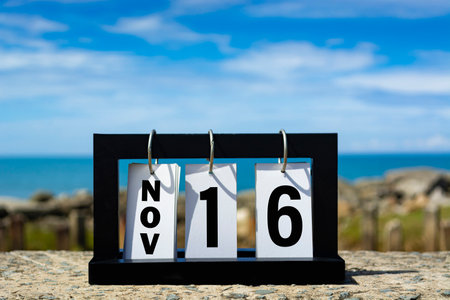 Nov 16 calendar date text on wooden frame with blurred background of ocean.の写真素材