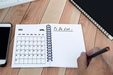 Businessman hands with pen writing to do list with April 2023 calendar on notebook. Copy space. Business concept.の写真素材