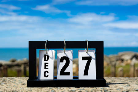 Dec 27 calendar date text on wooden frame with blurred background of ocean. Calendar date concept.の写真素材