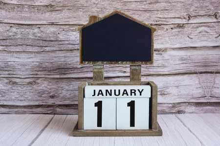 Chalkboard with January 11 date on white cube block on wooden table.の写真素材