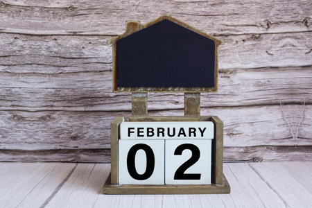 Chalkboard with February 02 calendar date on white cube block on wooden table.の写真素材