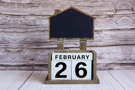 Chalkboard with February 26 calendar date on white cube block on wooden table.の写真素材