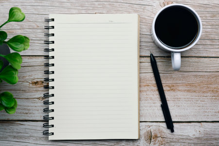 Directly above view of a desk with pen, notepad, plant and coffee. Flat lay. Copy space.の写真素材