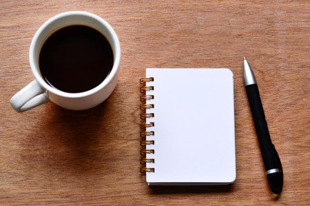 Directly above view of office desk with pen, notepad and coffee. Flat lay. Copy space.の写真素材