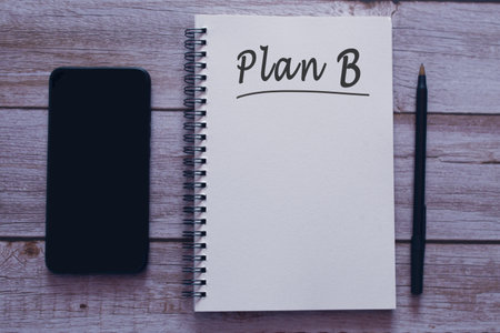 Plan B written on notepad with smartphone and pen on wooden desk.の写真素材