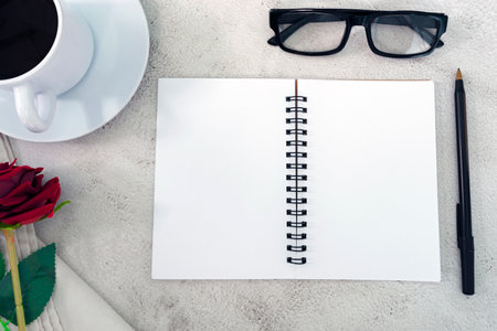Note book with pen, reading glasses, coffee and roses on marble table. Directly above. Flat lay. Copy space.の写真素材