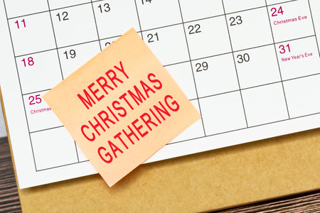 Merry Christmas Gathering words on a orange paper sticky note and stuck to a calendar background. Reminder concept.の写真素材