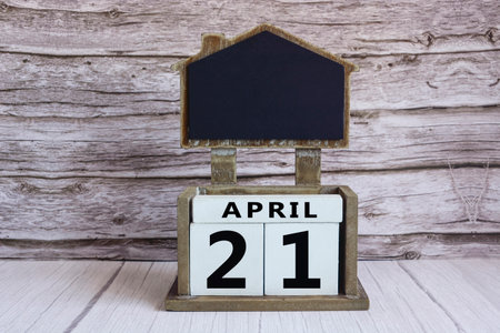 Chalkboard with April 21 date on white cube block on wooden table.の写真素材