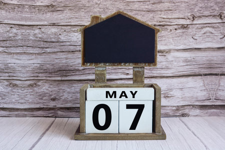 Chalkboard with May 07 date on white cube block on wooden table.の写真素材