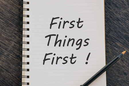 First Things First text on notepad with pen on wooden desk.の写真素材