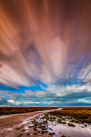 timelapse movement of clouds across marshland with a trackの写真素材