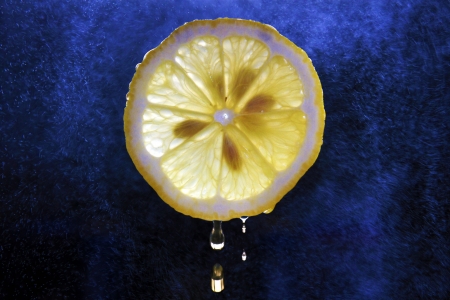 Juice dripping from a freshly sliced lemonの写真素材