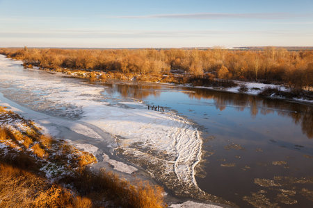 top view of the river covered with thin ice with wormwood