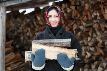 russian woman in Winter Clothes with firewoodの写真素材