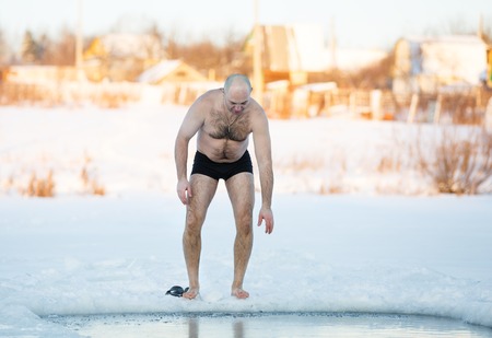 Winter-swimmer in ice-hole at lake in frosty dayの写真素材