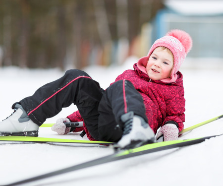 child sitting in  snow to winter ski clothingの写真素材