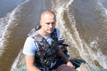 man in army fatigues moved by motor boatの写真素材