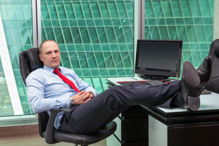 businessman relaxing at the office with his shoes on the desk
