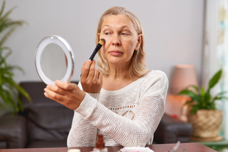 beautiful senior woman after applying make up holding a brushの写真素材