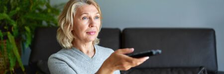 Mature senior woman watching television at homeの写真素材