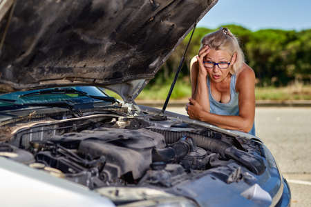upset driver woman in front of automobile broken car collision accident in city roadの写真素材