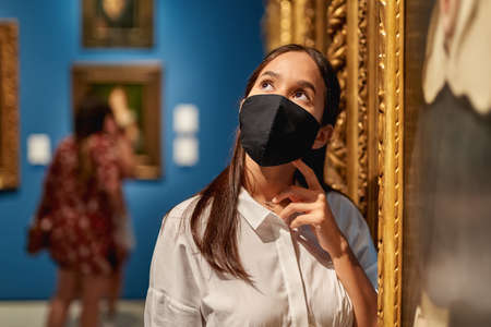 woman visitor wearing an antivirus mask in the historical museum looking at picturesの写真素材