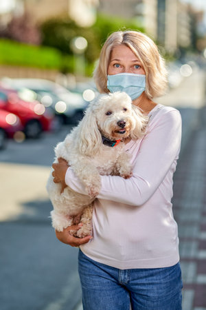 Portrait elderly woman with a dog outdoors an antivirus mask.