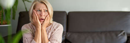 Woman suffering from a headache and stress holding her hands to her templesの写真素材