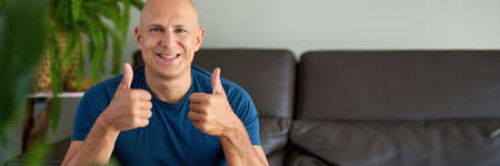 happy man looking at camera while sitting on sofaの写真素材