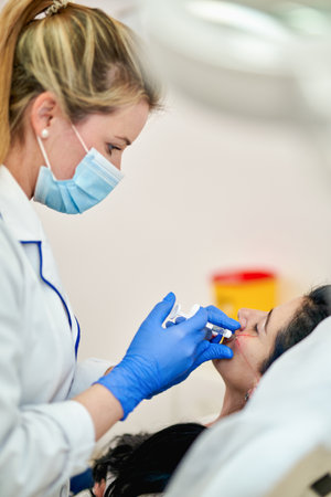 Close up of hands of cosmetologist making beauty injection. She is holding syringe. Woman is receiving procedure with enjoyment. High quality photoの写真素材