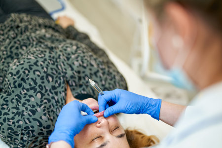 The doctor cosmetologist makes Lip augmentation procedure of a beautiful woman in a beauty salon....