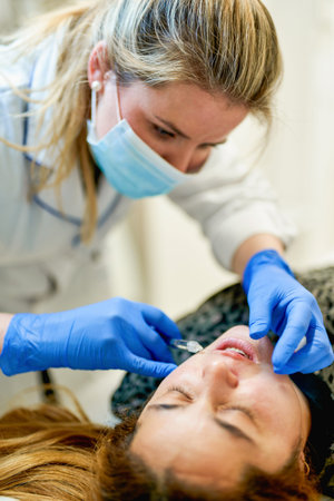 The doctor cosmetologist makes Lip augmentation procedure of a beautiful woman in a beauty...