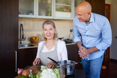 Mom and adult son in the kitchen preparing foodの写真素材