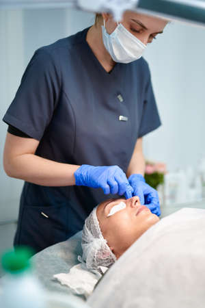 Cosmetologist doctor wiping woman face uses cotton pads after peeling procedure.Doctor is making beauty procedure in cosmetology clinic.の写真素材