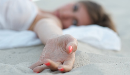 woman's hand lying on the sandの写真素材