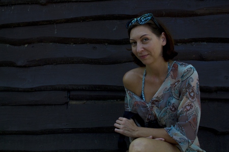 Cute woman posing at the camera. He smiles. Looks at you. Against the background of a wooden wall.の写真素材