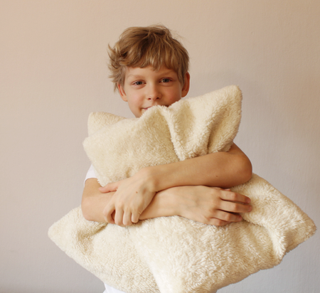 Boy is hugging a pillow. Pillow advertising. Looks into the camera. Smile.の写真素材