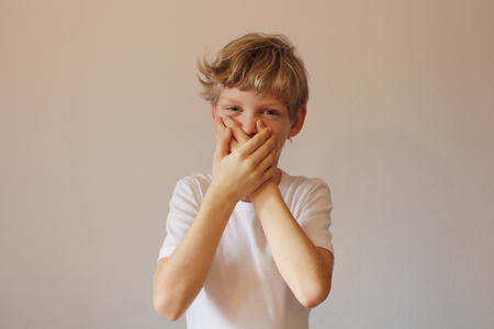 The boy covered his mouth with his palms. I will not say anything. Do not chat. Hand on lips.の写真素材