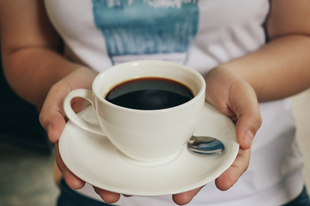 women hold a cup of Black coffee. Vintage tone. Selective Focus.の写真素材