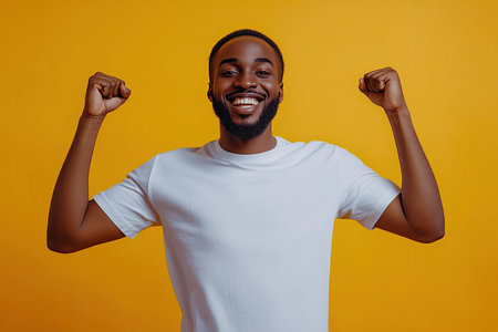 Cheerful african american man celebrating success isolated on yellow backgroundの素材