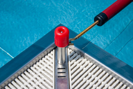 detail of a corner of a swimming pool with blue water and red bracketの写真素材