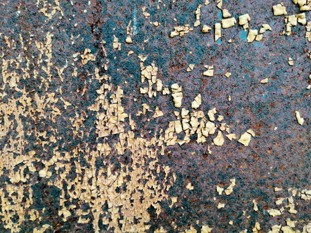 old rusted metal door with remnants of chipped light colored paint, grunge background